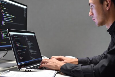 Asian man coding on laptop