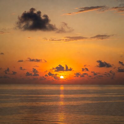 Sunrise over calm ocean with clouds