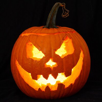 Lit Jack-o'-lantern pumpkin on black background