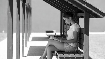 Woman reading book on bench shelter