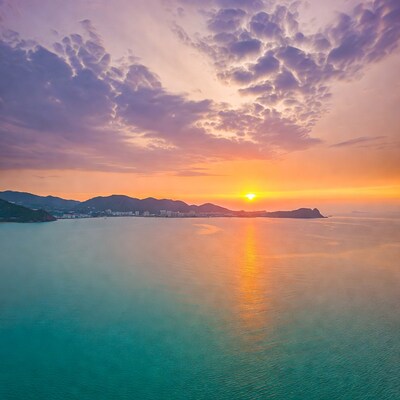 Sunset over sea with mountains and city
