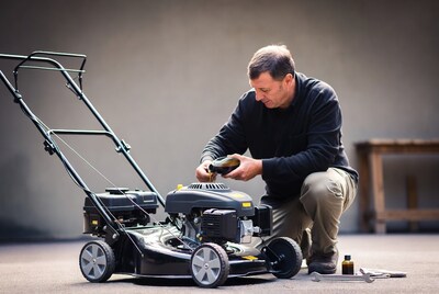Man pouring oil into lawnmower engine