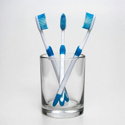 Three blue toothbrushes in glass