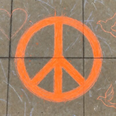 Orange chalk peace symbol on pavement