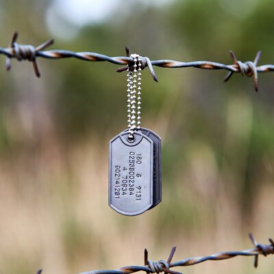 Dog tag hanging on barbed wire