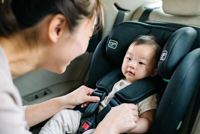 Asian mother buckling baby in car seat