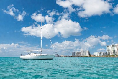 White sailboat on turquoise water near skyscrapers