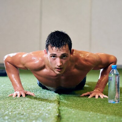 Sweaty man doing pushups on gym mat