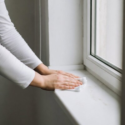 Woman cleaning window sill with cloth