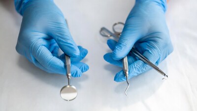 Gloved hands holding dental mirror probe