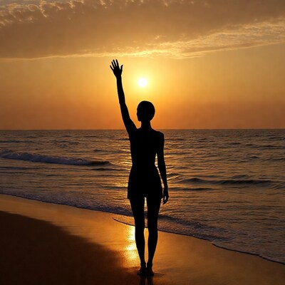 Silhouette woman raising hand at sunset beach