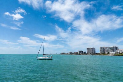 Sailboat on turquoise sea with city skyline