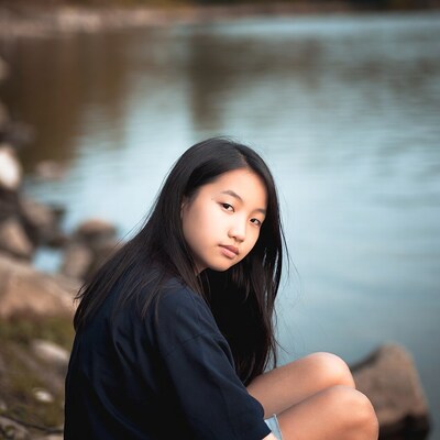 Asian girl sitting by lake