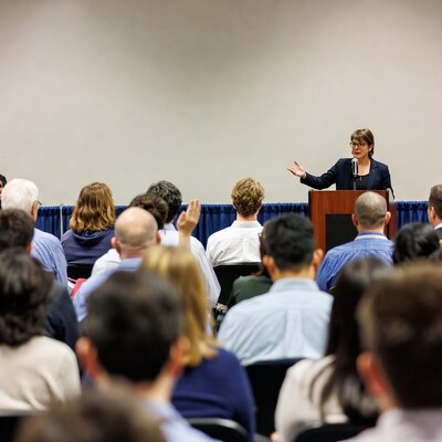 Woman speaking at podium to audience