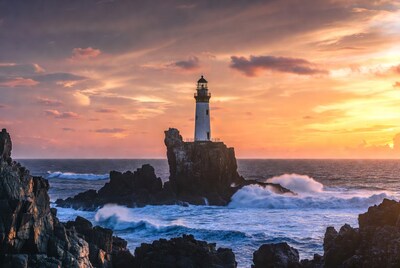 Lighthouse on rocky island at sunset