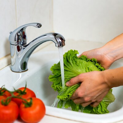 Woman washing lettuce under faucet