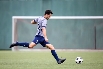 Soccer player kicking ball near goal