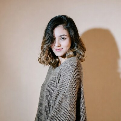Woman in beige sweater smiling sideways