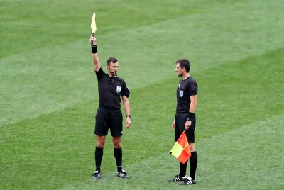 Two soccer referees holding flags on field