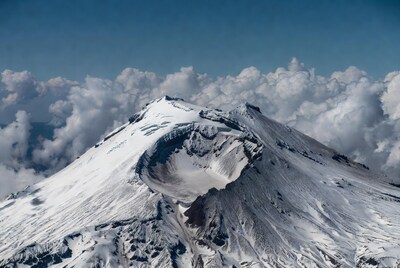 Snowy volcano crater with clouds