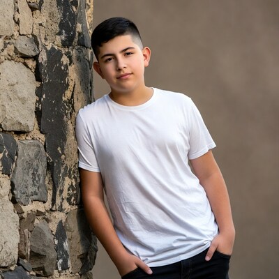 Latino boy leaning against stone wall