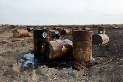 Rusty oil drums leaking on muddy ground
