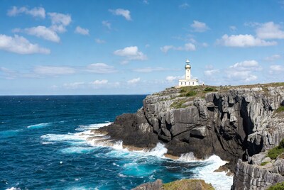 White lighthouse on rocky cliff overlooking ocean