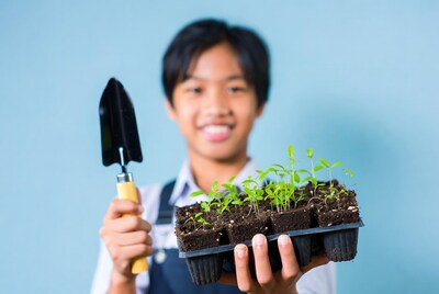 Asian boy holding seedlings and trowel