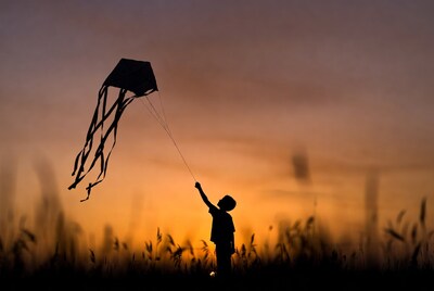 Boy flying kite silhouette at sunset