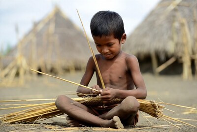 Asian boy weaving basket with reeds