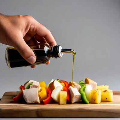 Hand pouring oil on chicken veggie skewers