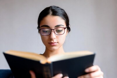 Young woman reading book with glasses