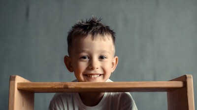 Boy smiling through wooden shelf