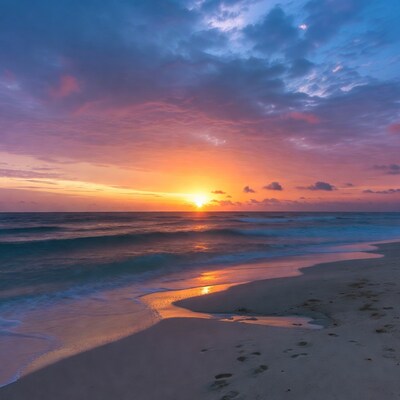Sunset over beach with footprints