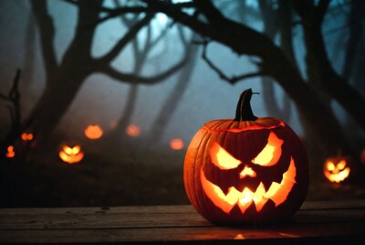 Jack-o'-lantern on wooden table in foggy forest