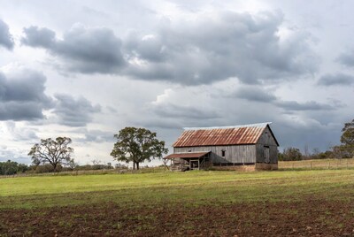Rusty Barn in Green Field Under Stormy Sky