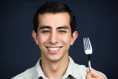 Young man holding fork smiling