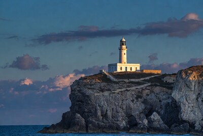 Lighthouse on cliff at sunset