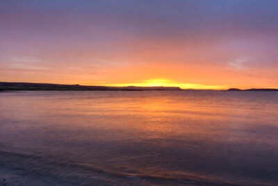 Sunset over calm sea and hills