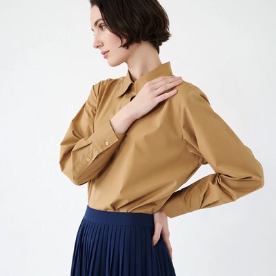 Woman in tan shirt and navy pleated skirt