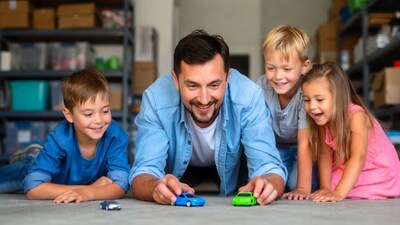 Father playing toy cars with kids in garage