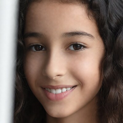 Smiling girl peeking from behind wall