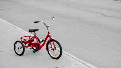 Red tricycle on gray pavement