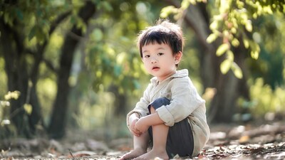 Asian toddler boy sitting in forest