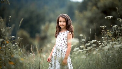 Girl in white floral dress among wildflowers