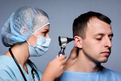 Doctor examining man's ear with otoscope