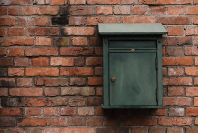 Green mailbox on brick wall