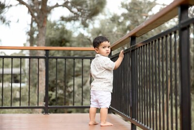 Asian toddler holding balcony railing