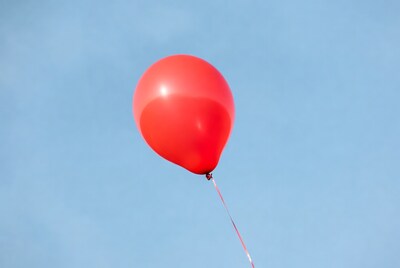 Red balloon floating in blue sky