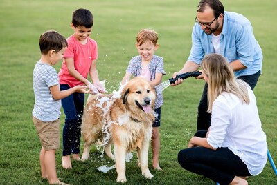 Family washing golden retriever with hose